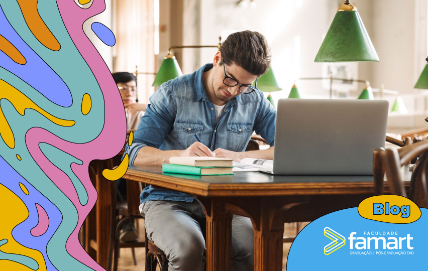 rapaz em sala de aula sentado na mesa com computador e livros