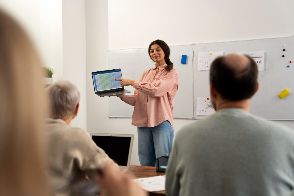 professora em sala de aula com computador na mão mostrando aos alunos