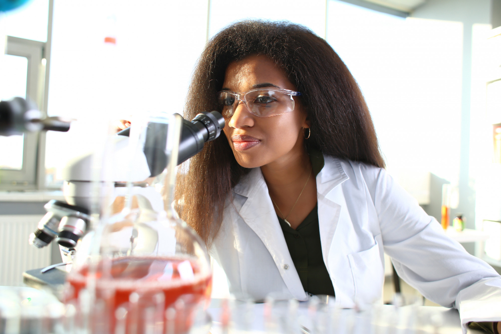 imagem de uma mulher em laboratório olhando no microscópio.